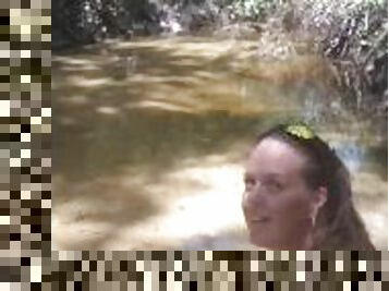 Cute long hair girl on her knees looking for shells to collect in popular spring creek